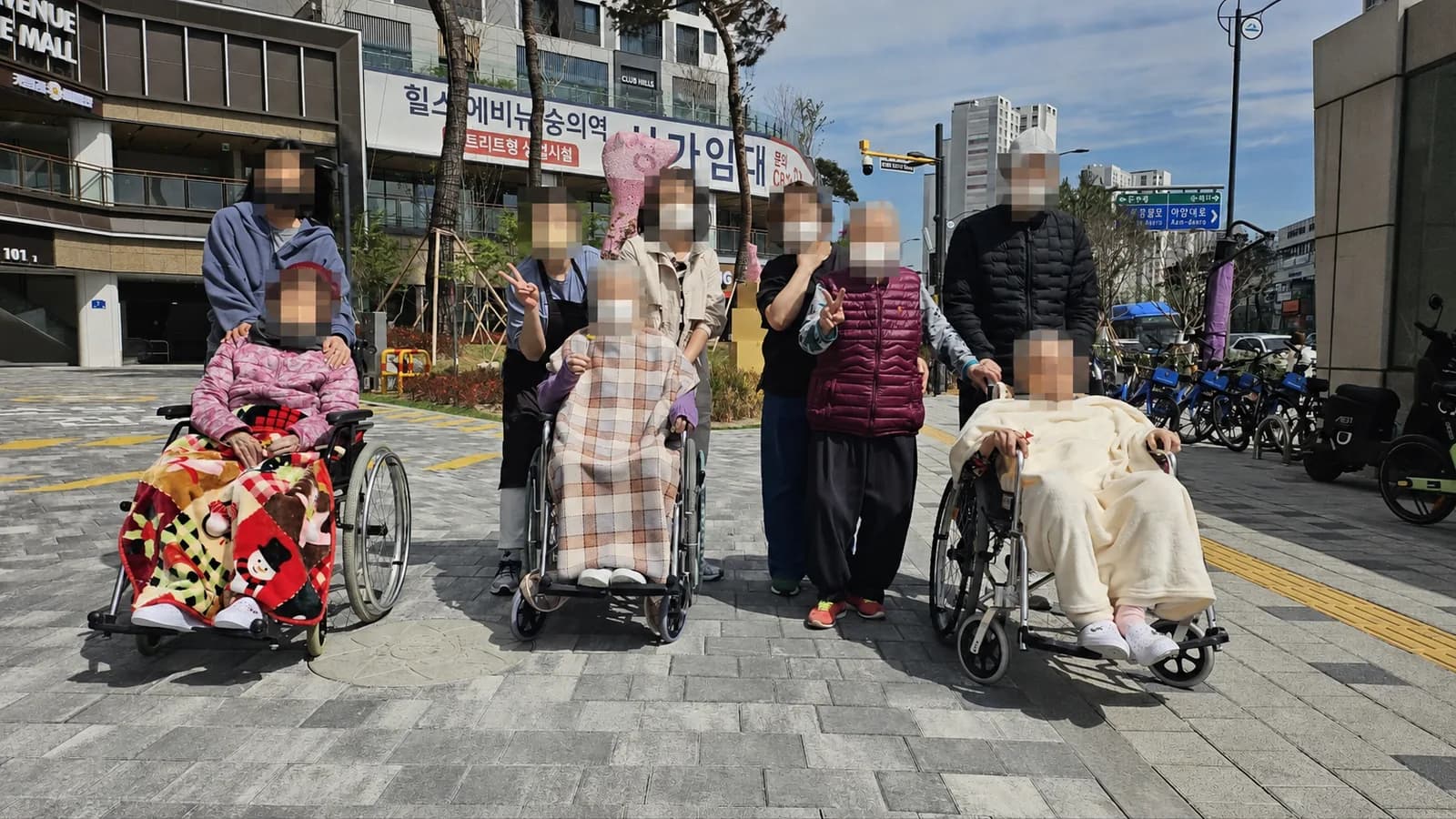 휠체어를 이용하는 어르신 곁에 동행인들이 함께 선 모습