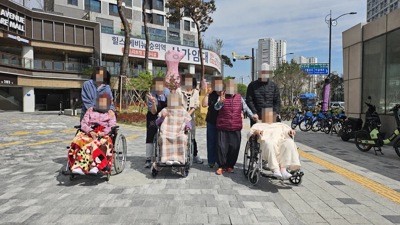 햇볕이 드는 동네 보행로에서 함께 외출한 어르신들과 동행인들