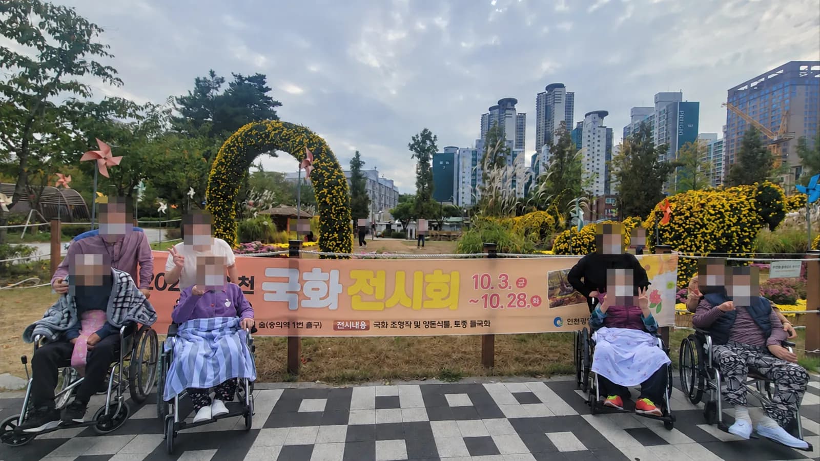 국화 전시 안내 현수막 앞에 모인 어르신들과 동행인들